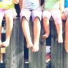 Fem barn med fargerike klær sitter på en høy trekasse i sommervarmen 