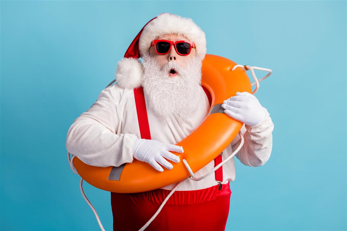 Julenissen har tatt på seg solbriller, klar for juleferie, og står med livbøyen rundt overkroppen - Klikk for stort bilde